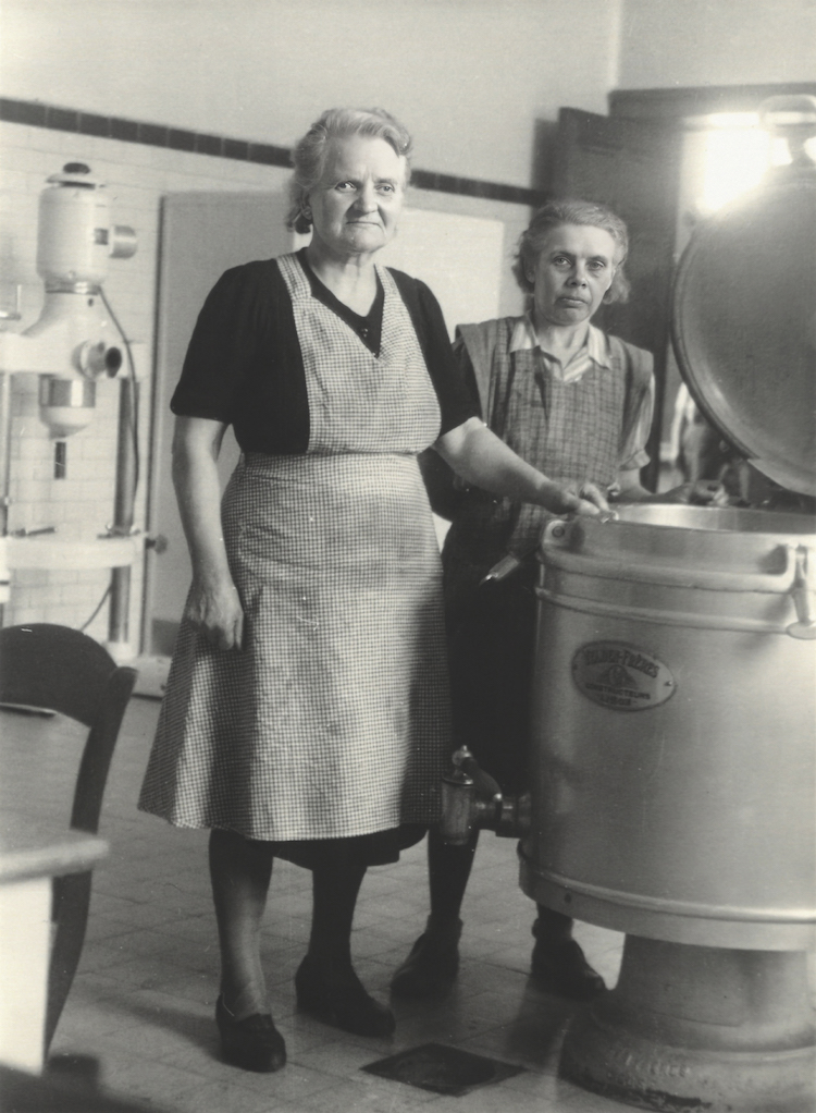 Keukenmedewerkers “Jeanne & Wiske” met een oude kookketel (d.d. 1953).